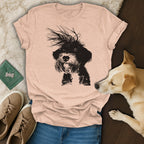 Black terrier dog graphic on a light pink t-shirt, next to dog and shoes.