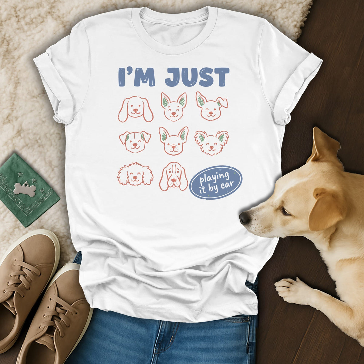 White t-shirt with "I'M JUST playing it by ear" and nine dog faces.