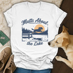 White t-shirt with blue graphic of dog jumping into a lake with text "Mutts About the Lake".