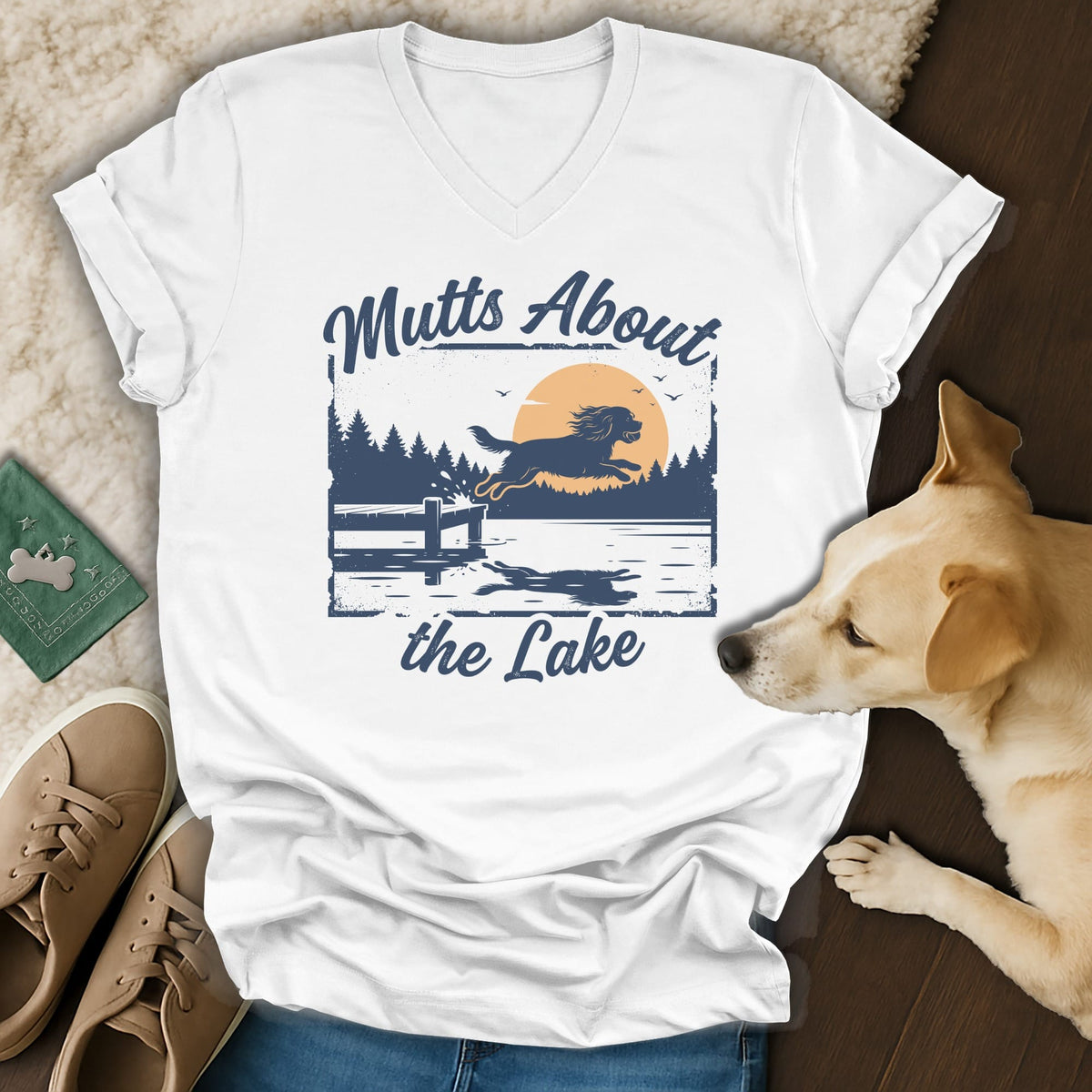 White t-shirt with blue graphic of dog jumping into a lake with text "Mutts About the Lake".