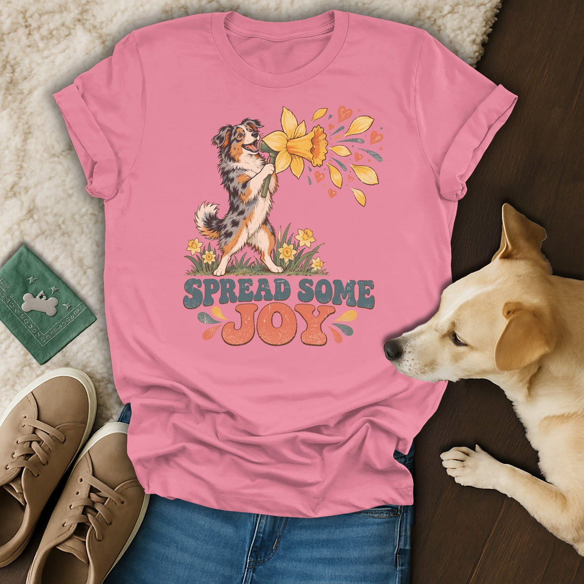 Pink t-shirt with a graphic of an Australian Shepherd holding a daffodil and the text "SPREAD SOME JOY."