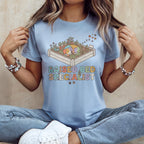 Light blue t-shirt with a graphic of a sleeping dog in a garden bed and the text "Raised Bed Specialist".