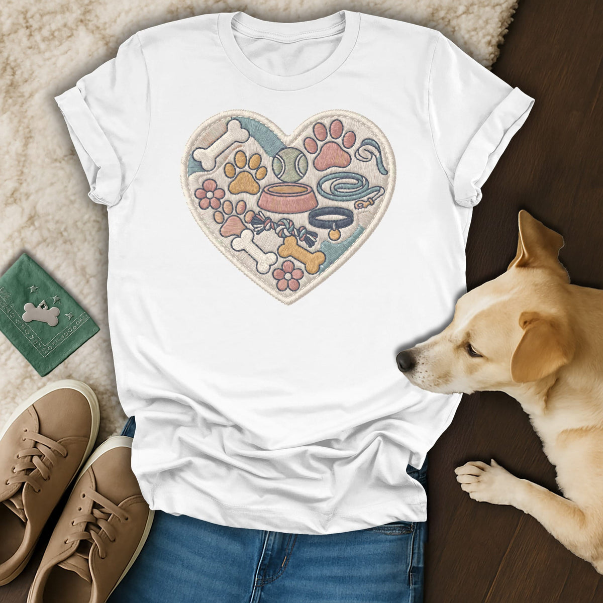 White t-shirt with embroidered heart of dog toys, paws, bones, and flowers.