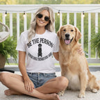 Woman in white t-shirt with dog graphic sitting with Golden Retriever.