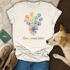 T-shirt with rainbow paw print bouquet and "love grows here" text.
