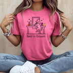 Woman wearing pink t-shirt with "Best in Groom" text and illustration of dog at vanity.