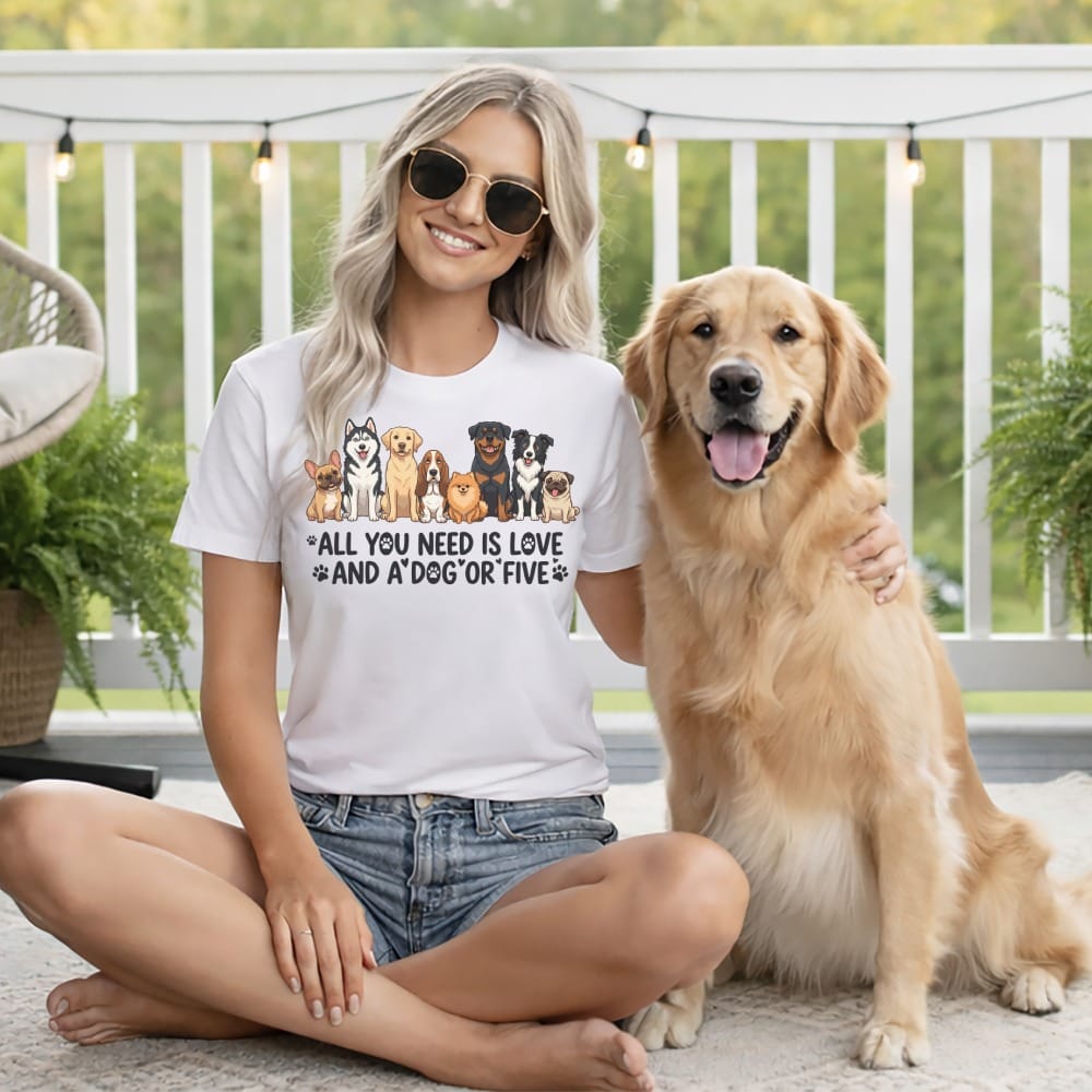 Woman wearing a white t-shirt with dogs and text, sitting with a golden retriever.