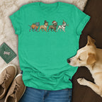 Green t-shirt with four dogs in festive outfits: pumpkin, pilgrim, Santa, and party.