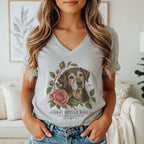 A person wears a heather-gray V-neck t-shirt featuring a botanical illustration of an older dog and pink roses, with the text Gray Muzzle Rose below.