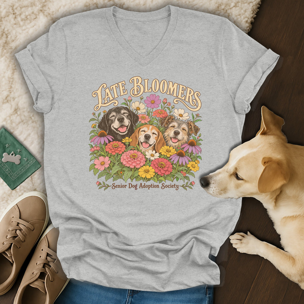 Grey V-neck t-shirt featuring a graphic of three smiling dogs surrounded by colorful flowers and the text Late Bloomers.