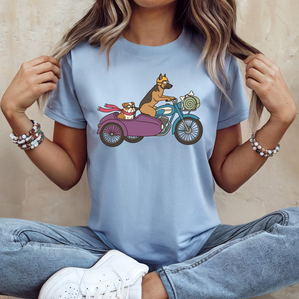 German Shepherd driving motorcycle with Bulldog in sidecar, wearing goggles and scarves.