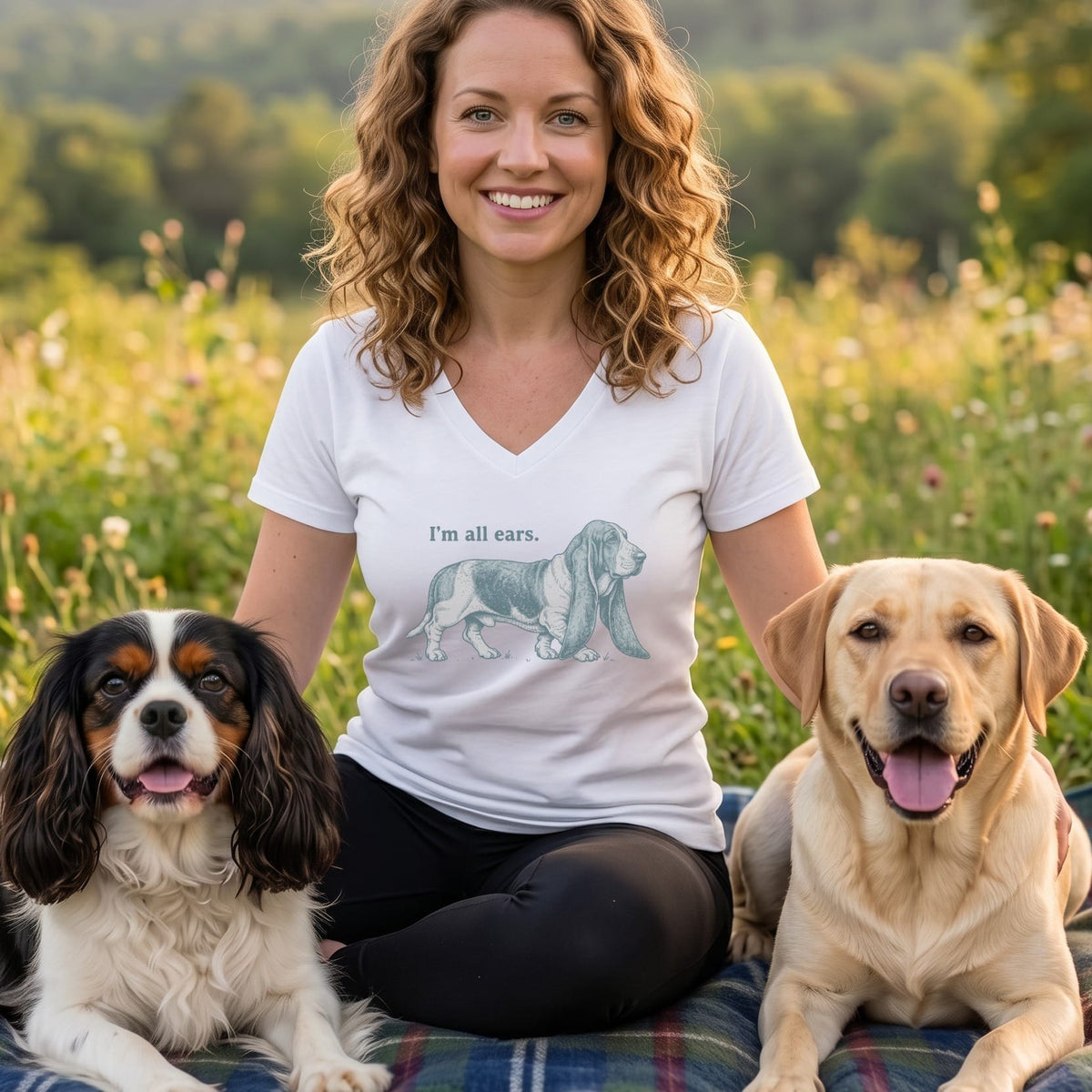 Woman in white t-shirt with "I'm all ears" and basset hound graphic, with two dogs.