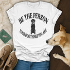 White t-shirt with black distressed text "BE THE PERSON YOUR DOG THINKS YOU ARE" and a dog silhouette.