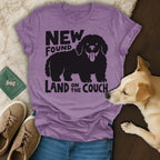 Black silhouette of a happy dog on a purple t-shirt that reads "New Found Land on the Couch".