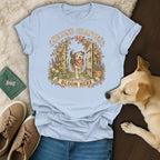 Light blue t-shirt featuring a dog graphic, surrounded by sneakers and a sleeping dog.