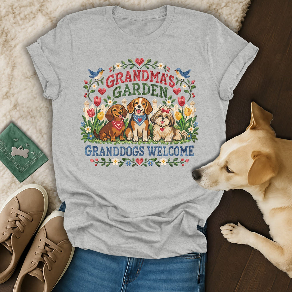 Heather gray t-shirt with cross-stitch style graphic reading Grandma's Garden Granddogs Welcome surrounded by three dogs and flowers.