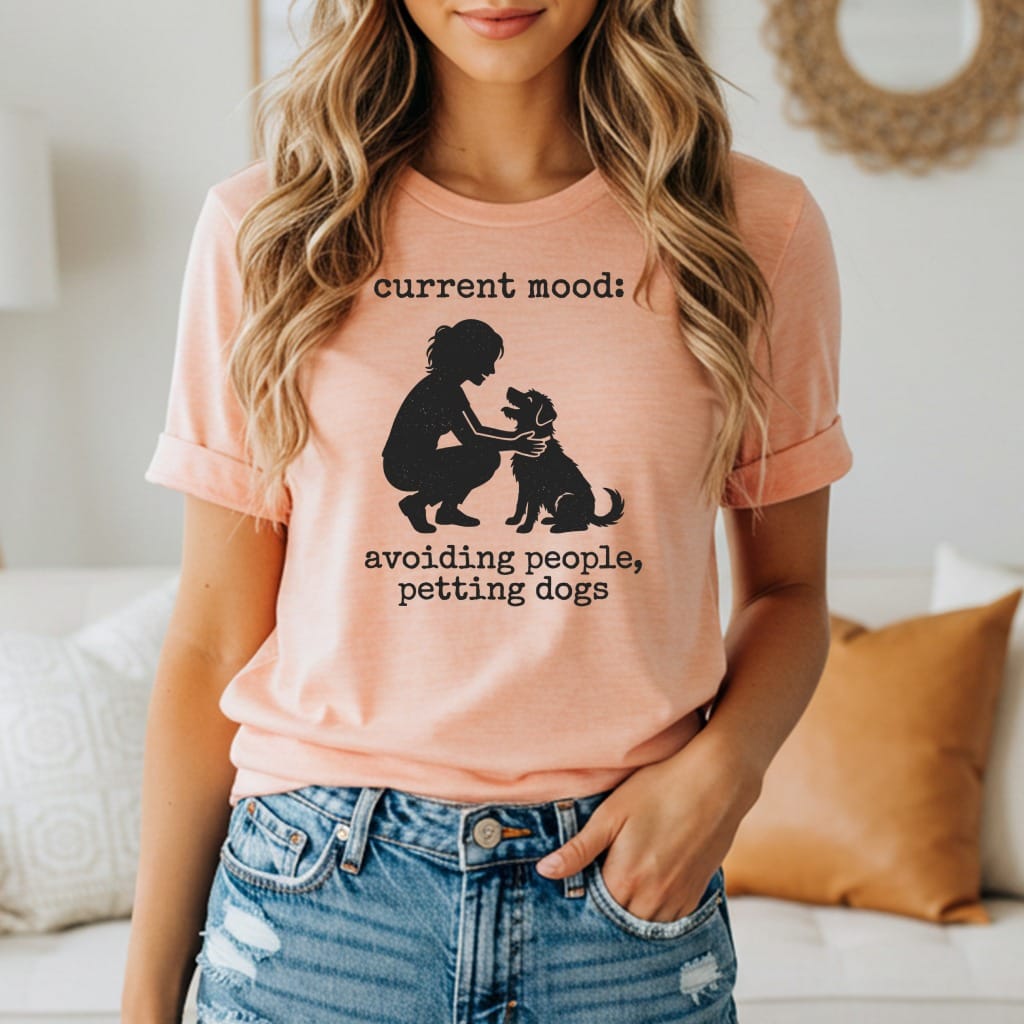 Woman wearing peach t-shirt with silhouette of person and dog, and text "current mood: avoiding people, petting dogs".
