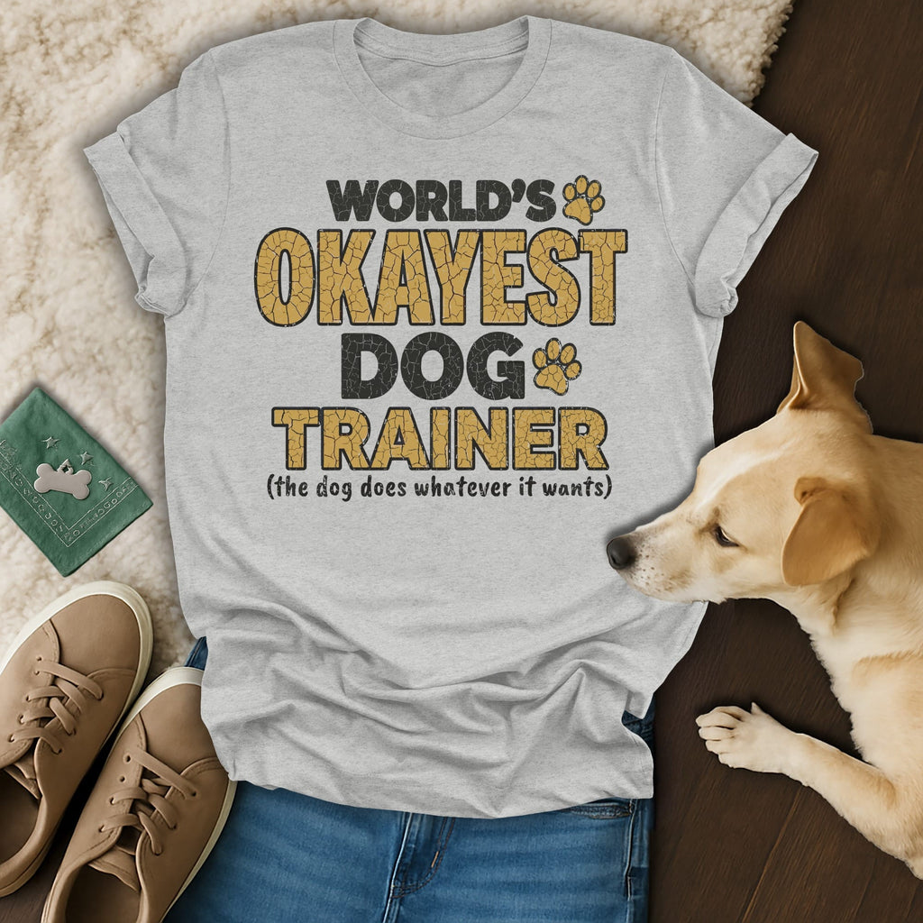 Grey t-shirt with text "World's Okayest Dog Trainer (the dog does whatever it wants)".