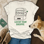 White t-shirt with cartoon slot machine featuring dog faces and "Lucky Paw Shoppe" text.