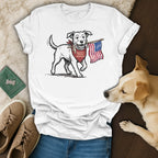 Dog wearing a bandana holds American flag in mouth on a t-shirt.