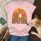 Light pink t-shirt featuring a retro graphic of a pit bull surrounded by flowers with the text Pittie Mom.