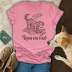 Pink t-shirt with a stylized dog illustration surrounded by clouds and raindrops.