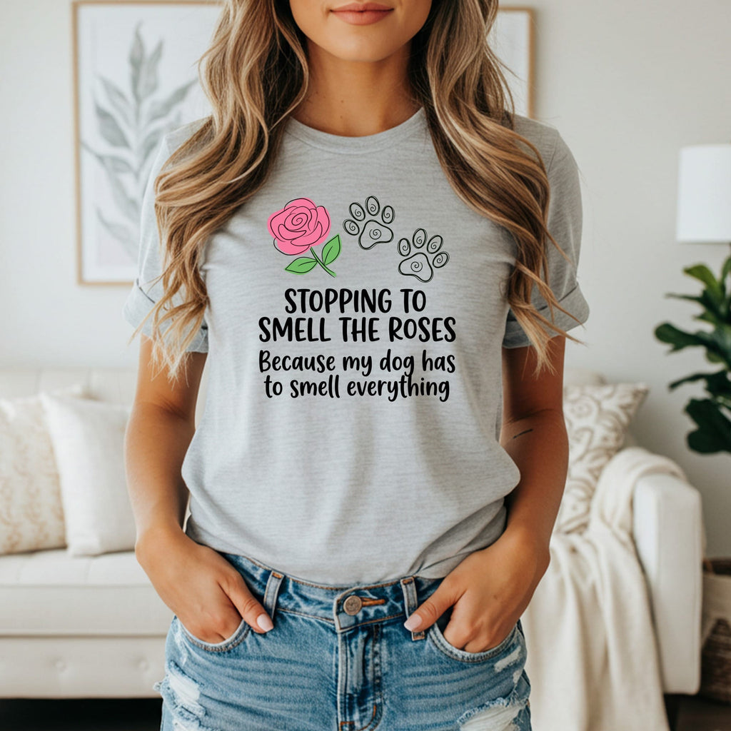 Light gray t-shirt with pink rose, paw prints, and text "Stopping to smell the roses because my dog has to smell everything."