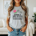 Light gray t-shirt with pink rose, paw prints, and text "Stopping to smell the roses because my dog has to smell everything."