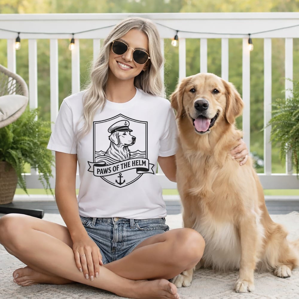 Woman wearing a t-shirt with a nautical dog graphic sits with a golden retriever.