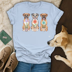 Watercolor illustration of three dogs sitting with potted flowers on light blue t-shirt.