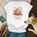 White t-shirt with a cartoon dog in a pumpkin and fall leaves, text "Cutest in the Patch".