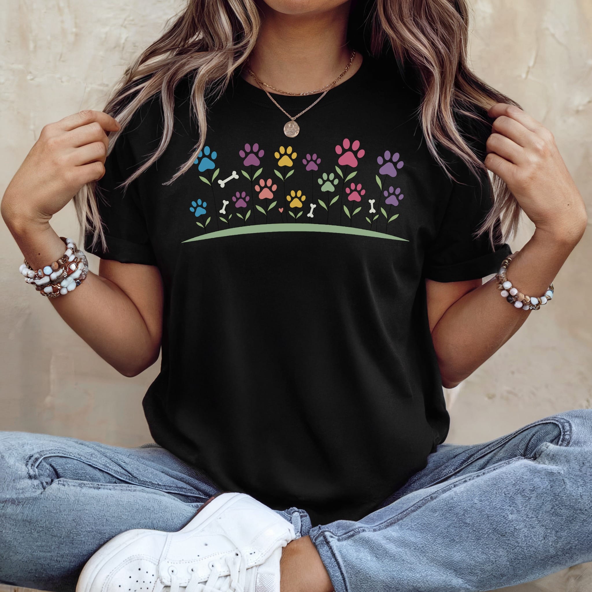 Black t-shirt with colorful paw prints and flowers graphic.