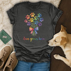 Dark t-shirt with a colorful bouquet of paw prints and the text "love grows here."