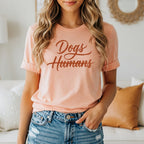Peach t-shirt with "Dogs Humans" in cursive text.