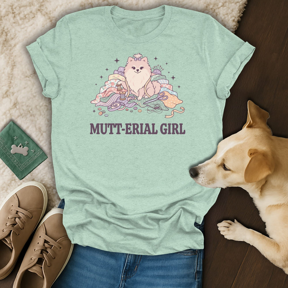 Light green t-shirt with a graphic of a fluffy dog and sewing supplies, reads "MUTT-ERIAL GIRL".