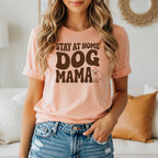 Peach t-shirt with brown text "STAY AT HOME DOG MAMA" and a small dog illustration.