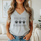 Grey t-shirt with black text and paw prints reading "MY DOG IS NOT SPOILED. I'M JUST VERY OBEDIENT."