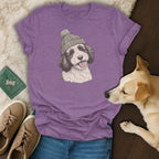 Purple t-shirt with a sketched dog wearing a knitted hat.