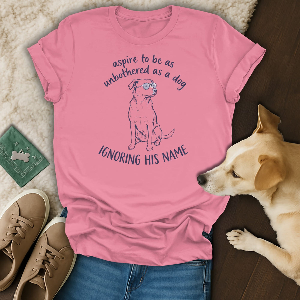 Pink t-shirt with a drawing of a dog wearing sunglasses and the text "aspire to be as unbothered as a dog ignoring his name".