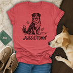 Red t-shirt with a black outline drawing of an Aussie dog and "Aussie-Tumn" text.