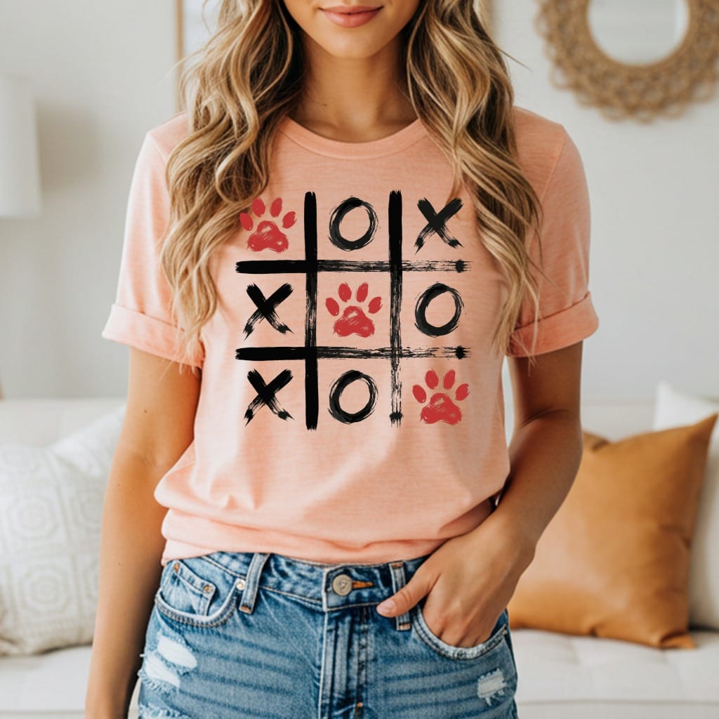 Peach t-shirt with a black and red paw print tic-tac-toe graphic.