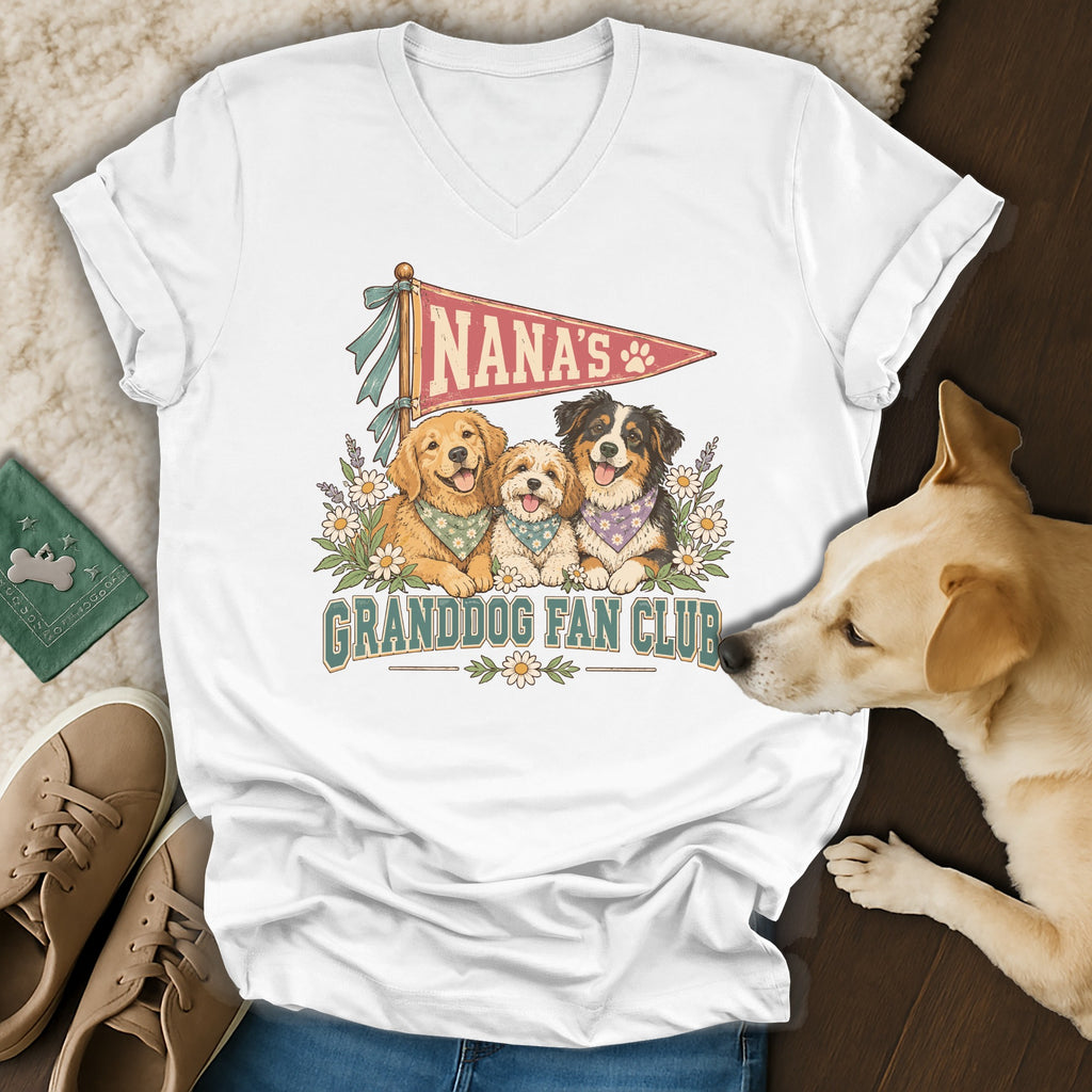 A white v-neck t-shirt featuring a graphic of three dogs and the text Nana's Granddog Fan Club.