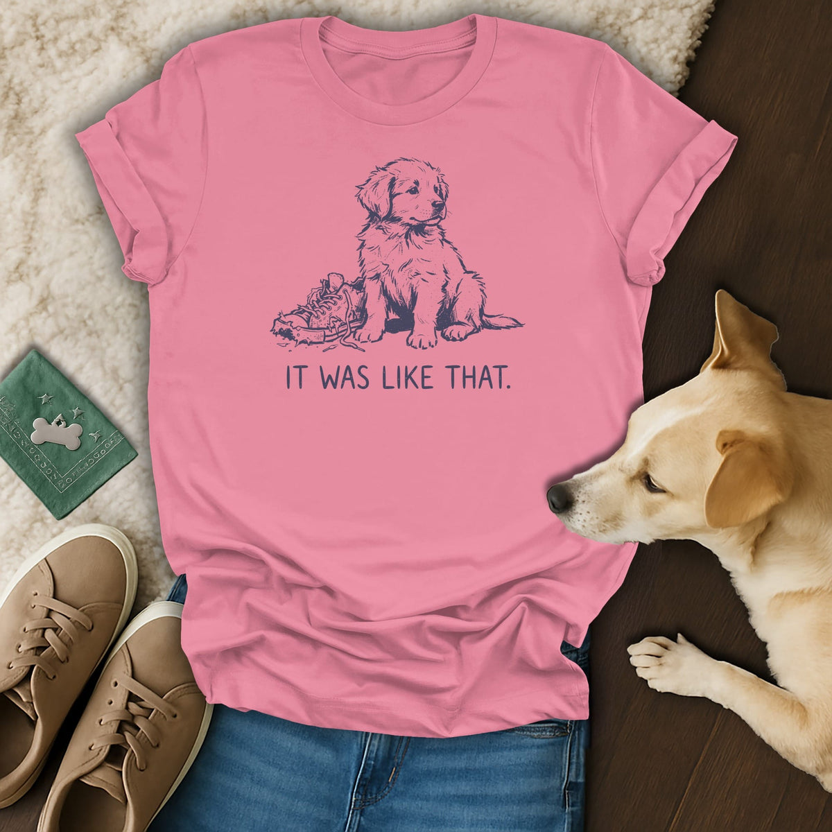 Pink t-shirt with a blue line drawing of a puppy next to a shoe and text.