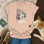 Peach t-shirt with illustration of black and white dog wearing a knitted hat.