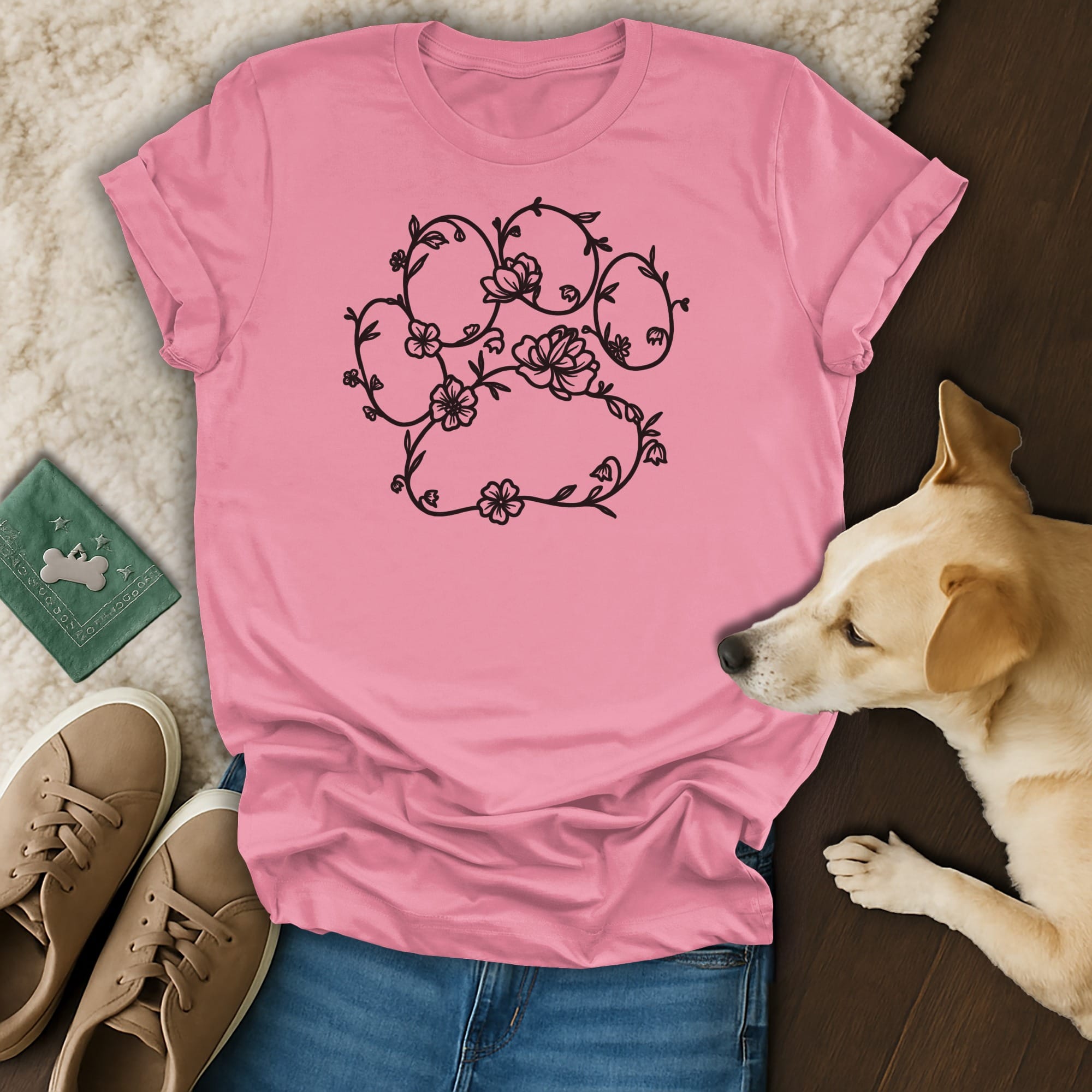 Pink t-shirt with black floral paw print design and dog nearby.