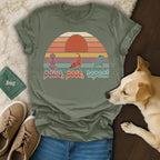 Olive t-shirt with sunset graphic and "paws, pose, repeat" text.