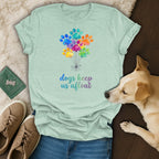 Light mint t-shirt with colorful paw print balloons and text "dogs keep us afloat."