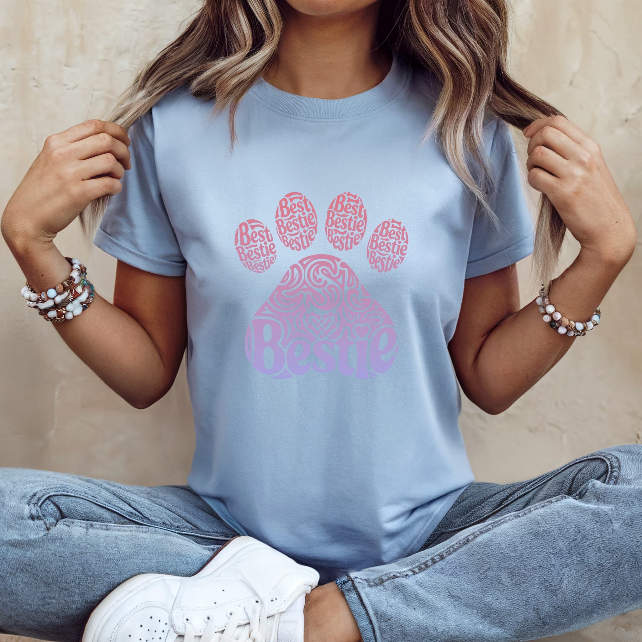 Pale blue t-shirt with a pink ombre paw print graphic made of "Bestie" text.