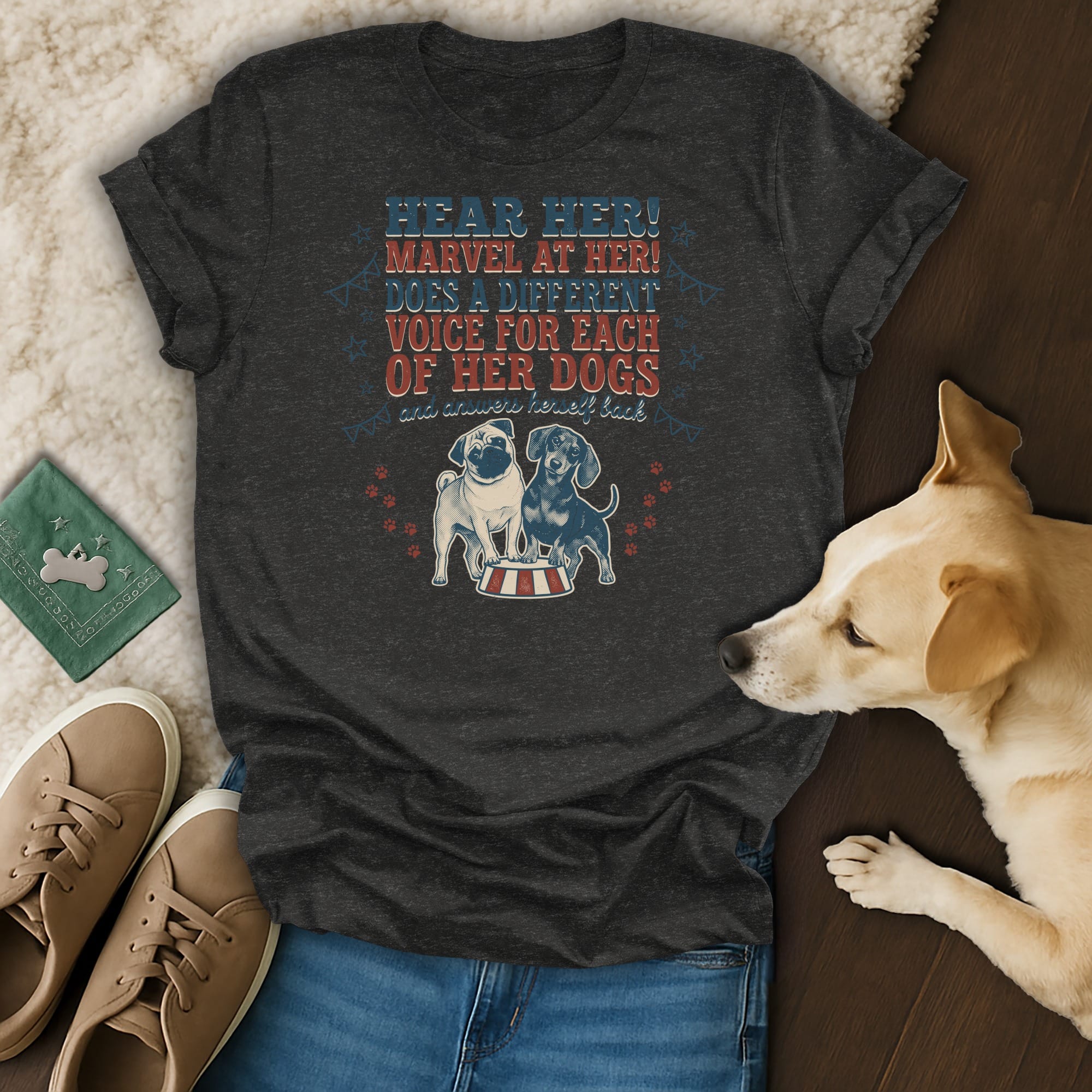 Dark t-shirt with "Hear her! Marvel at her! Does a different voice for each of her dogs and answers herself back" text.