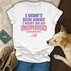 White t-shirt with pink and purple text reading "I didn't run away I went on an unsupervised adventure."
